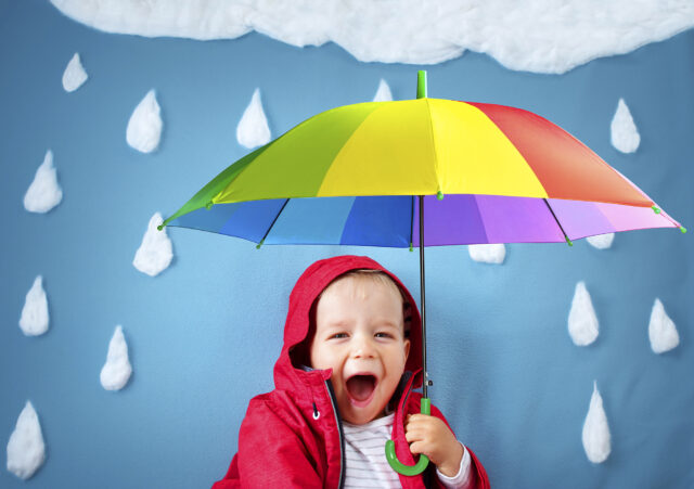 Little boy on blue background in coat with drop shapes